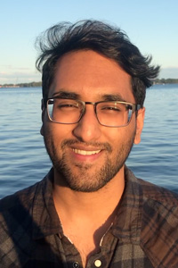  Fourth-year Victoria College student Anvesh Jain standing in front of a body of water.