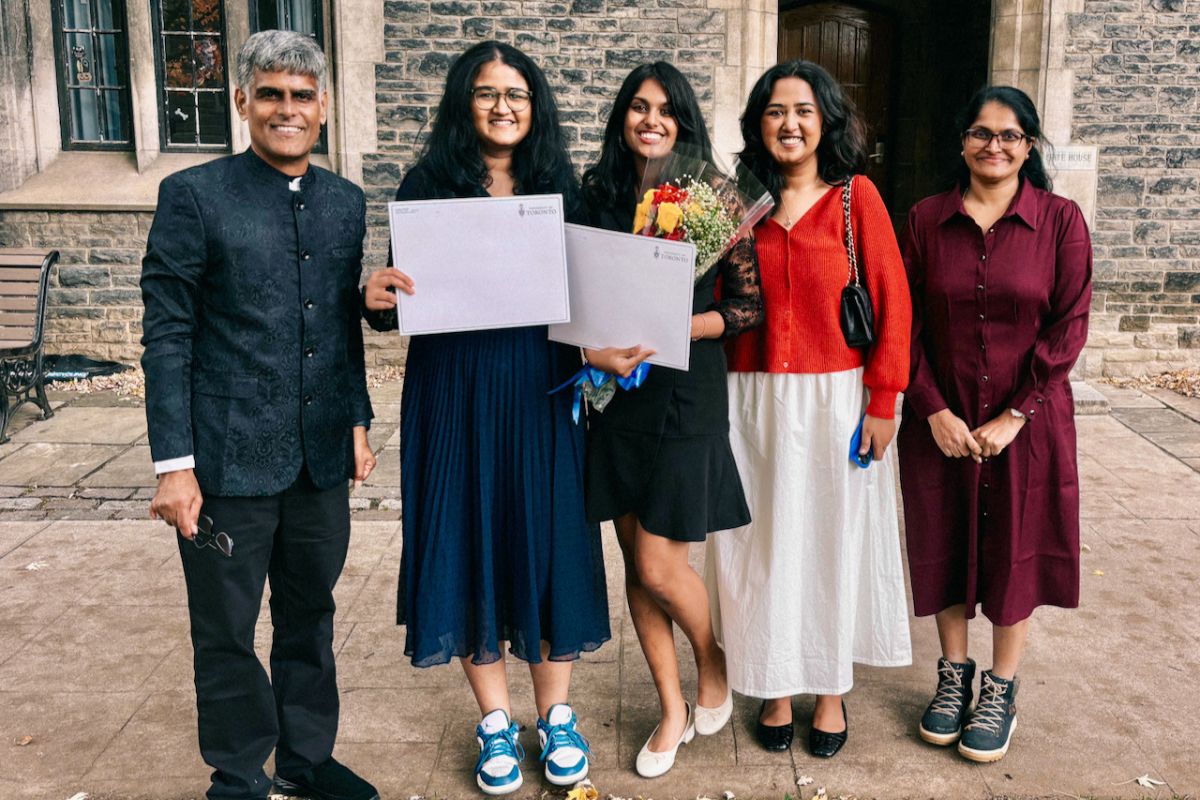 Devika Gopakurnar, new graduate, stands beaming with her family surrounding her.