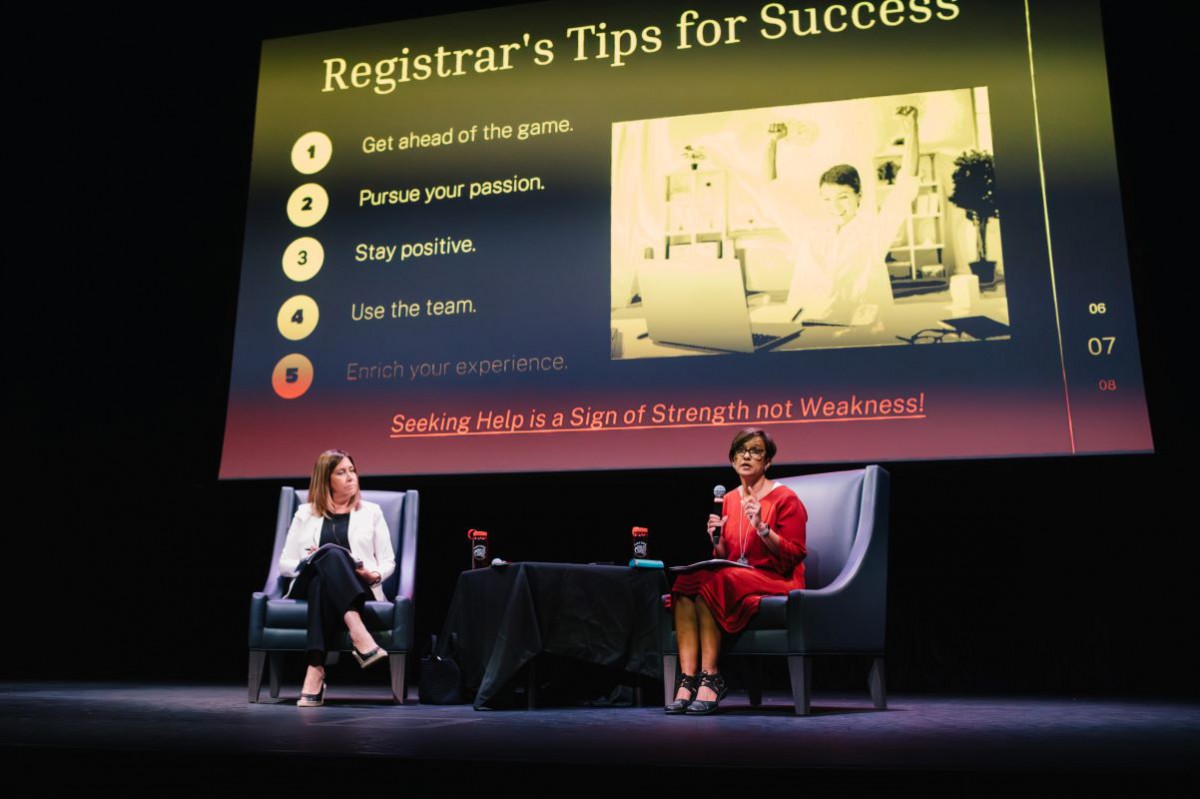 The Dean and Registrar sit on a stage during a talk, responding to questions asked by students.