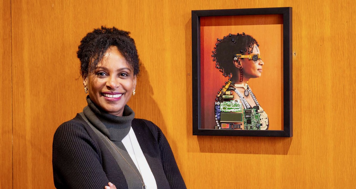 Rhonda McEwen standing next to a self-portrait in her office.